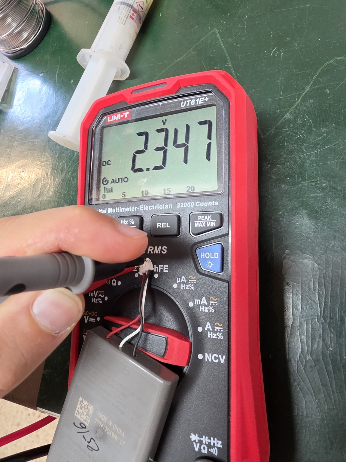 Multímetro UNI-T midiendo 2,347 V en la batería de un mando PS5 DualSense durante el diagnóstico